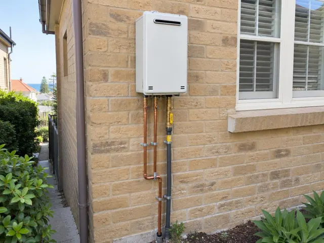 Wall-mounted hot water unit with copper and insulated pipework on a brick exterior wall in Coogee